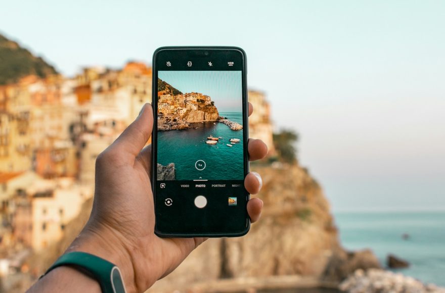 person holding a phone near cliff during daytime