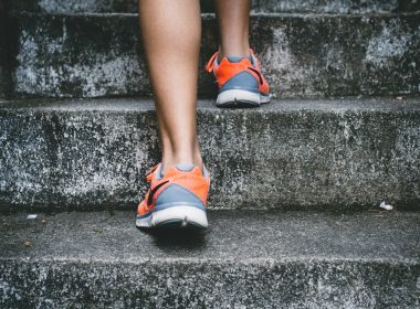 person wearing orange and gray Nike shoes walking on gray concrete stairs