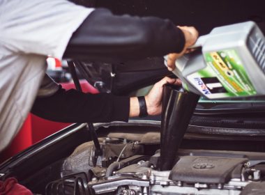 man refilling motor oil on car engine bay