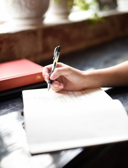 a person writing on a piece of paper with a pen